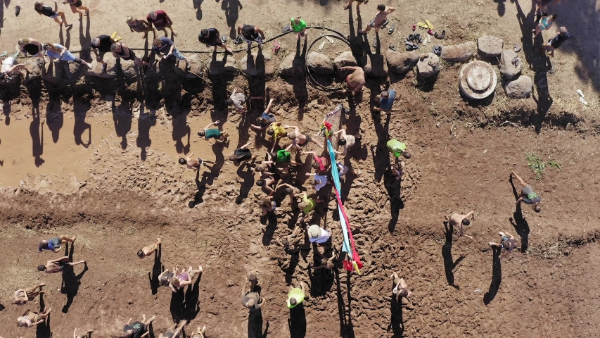 Aerial footage of People taking part in a sprint run contest at a Mud festival.