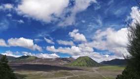 Time lapse of bright blue sky with clouds above Bromo national park, view on Bromo volcano and green hill.