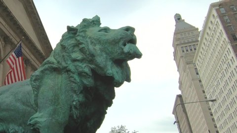 Chicago , Illinois / United States - 06 27 2019: Closeup view of The lion sculpture, in front of the Art institute of Chicago, Illinois, United States, Usa. American flag and buildings, skyscrapers.