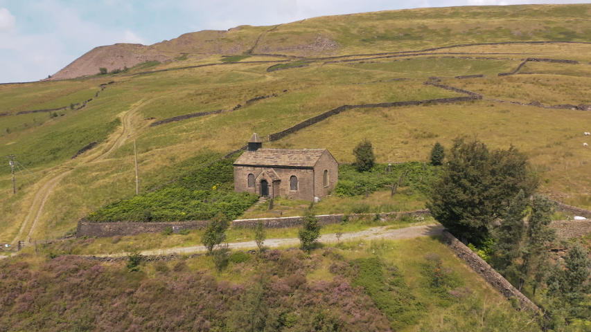 4K Aerial footage panning around a church revealing the beautiful Peak District National Park and surrounding reservoirs in Woodhead, Summer 2019