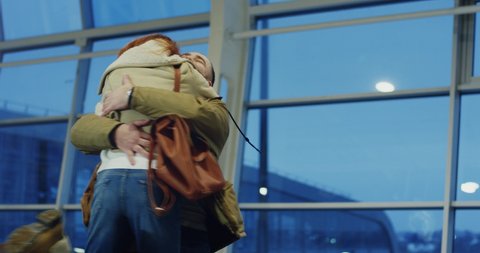 Caucasian young good looking happy and cheerful boyfriend and girlfriend meeting and hugging in the airport or train station.