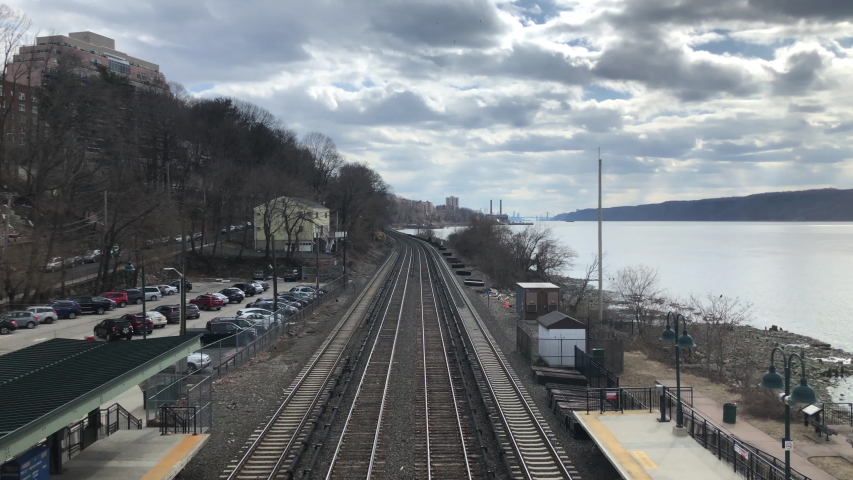 commuter train tracks along the water river on a grey spring day