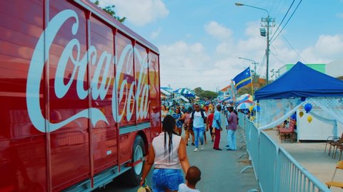 Willemstad / Curaçao - 03 03 2019: People walk by a moving Coca Cola truck during a Carnival parade in Willemstad, Curacao, Slow Motion
