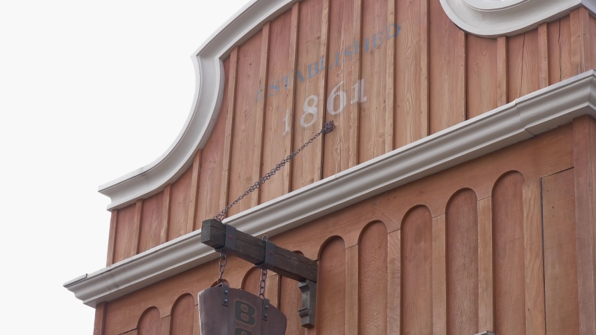 Old boot repair placard hanging out the front of a shop.