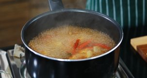 Close up scene video of someone cooking Tom Yum Kung in kitchen, it a Thai spicy soup that made from herbs and shrimp.

