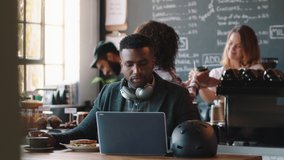 young african american man using laptop in cafe browsing online listening to music wearing headphones enjoying mobile computer technology - Powered by Shutterstock - Get 15% off with code: PIKWIZARD15
