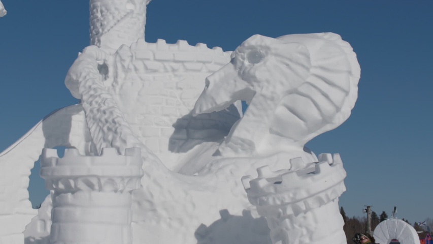 A castle and dragon carved in fine detail by a professional snow sculptor, static shot
