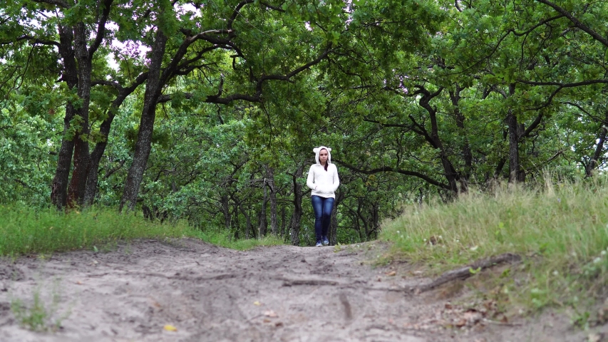 Anonymous woman walking in park. Back view of young female walking along path in quiet autumn park