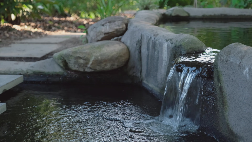 Water peacefully cascades over smooth gray river stones in an Asian style garden water feature in Raleigh, North Carolina