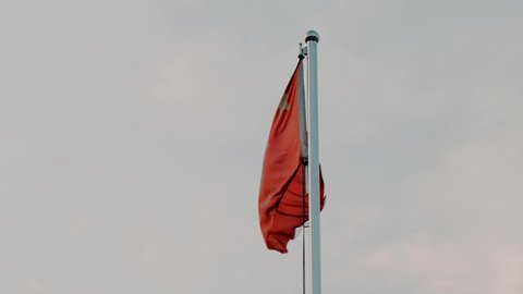 Waving Chinese Flag. Old flag of the People's Republic of China waving in the wind against the gray sky.