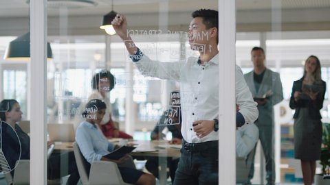 young asian businessman writing on glass whiteboard team leader training colleagues in meeting brainstorming problem solving strategy sharing ideas in office presentation seminar 4k