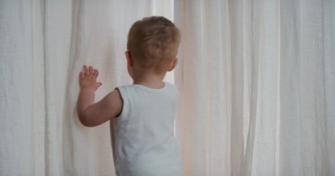 funny baby playing hiding behind curtains happy toddler having fun game of hide and seek enjoying childhood fun at home 4k