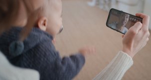 mother and baby using smartphone having video chat with best friend waving at toddler happy mom enjoying sharing motherhood lifestyle on mobile phone screen