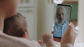 young mother and baby having video chat with grandfather using smartphone waving at grandchild enjoying family connection chatting on mobile phone