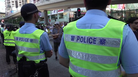 HONG KONG – 1 JULY 2019: Police watch protesters preparing for annual pro democracy rally and anti extradition law protests in Hong Kong