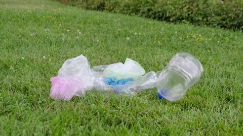 Plastic bottles and other rubbish falling on the lawn. Waste falls on the grass. Pollution of nature by plastic and polyethylene