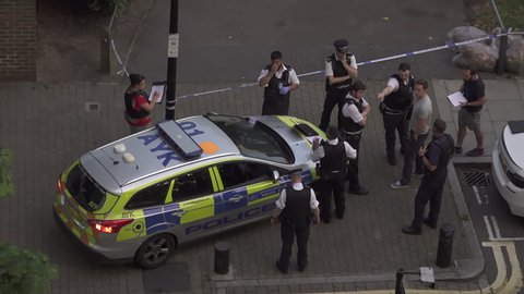 London / United Kingdom (UK) - 07 25 2019: A large group of police officers stand around a patrol car at a knife crime scene