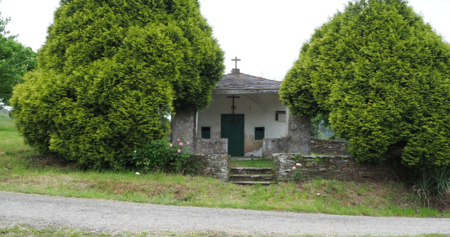 Hiking girl passing a small chapel while it rains.