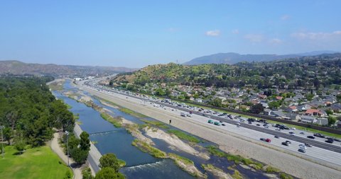 Aerial Drone stationary over heavy traffic on the 91 freeway with Santa Ana River in the foreground and homes and Anaheim Hills in the background in Orange County, California