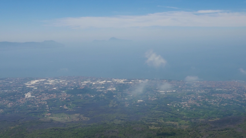 Aerial above the clouds view of Napoli cityscape with sea in the background 