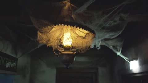 Old style vintage blinking lamp full of artificial spider net in a dimmed scary room