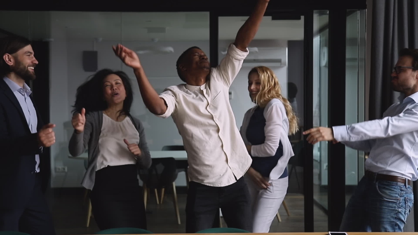 Motivated funny diverse business team people dancing celebrating success at corporate party on friday, happy friendly multiracial coworkers group having fun together enjoy victory dance in office | Shutterstock HD Video #1034587586