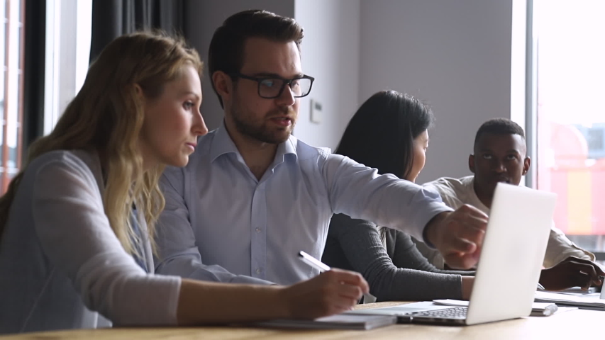 Helpful experienced male boss mentor teacher instructing young female intern trainee new worker making notes explaining new online project looking at laptop computer at apprentice course in office Royalty-Free Stock Footage #1034587652