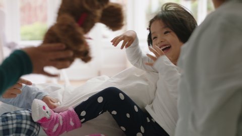 happy asian family with children jumping on bed playing with mother and father having fun on weekend morning excited little kids enjoying game with parents at home 4k footage