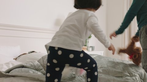 happy asian children jumping on bed waking up mother and father enjoying playful morning with kids on weekend at home 4k footage