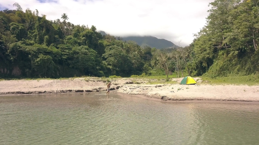 Flying around the couple walking on the water in lake. Camping on wild nature.