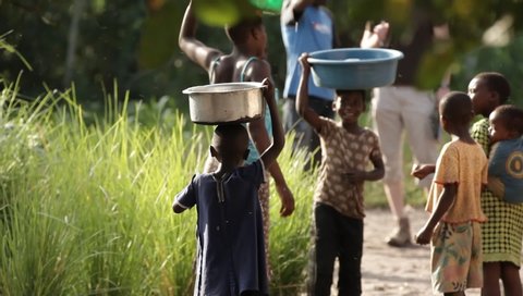 Lilongwe, Malawi - 01 18 2019: 
  Woman and kids carrying buckets of water to local village