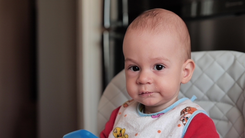 Mother feeds the baby. One-year-old old baby boy eats food, spoon-feeding