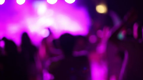 A crowd of people in a disco, no focus. Blurred image dancing people in a nightclub among bright lights on the background.