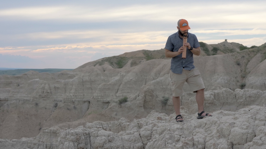 Man playing wood flute instrument in the Badlands of South Dakota