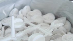 A large number of small white plastic parts in the factory.