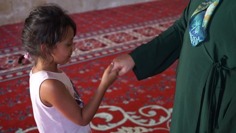 the little girl kisses the hand of her mother's elders. Muslims kiss the hand of old people on religious holidays. Victim and Ramadan feast