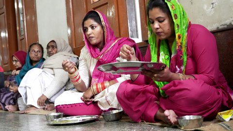 AMRITSAR, INDIA - MARCH 18, 2019: group of women eating in golden temple's communal food hall at amritsar, india