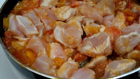 Homemade kitchen. Making sauce or dressing for pasta. Fresh tasty vegetables, tomatoes, onions, pepper, fried and mixed in deep frying pan with sliced chicken meat.