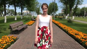 Young beautiful girl in a flowers dress walking in summer park.