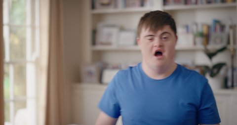 funny teenager boy with down syndrome dancing in living room special needs kid having fun celebrating with silly dance moves enjoying happy weekend at home 4k