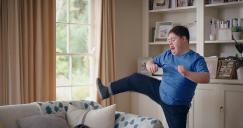 funny teenager boy with down syndrome dancing in living room special needs kid having fun celebrating with silly dance moves enjoying happy weekend at home 4k