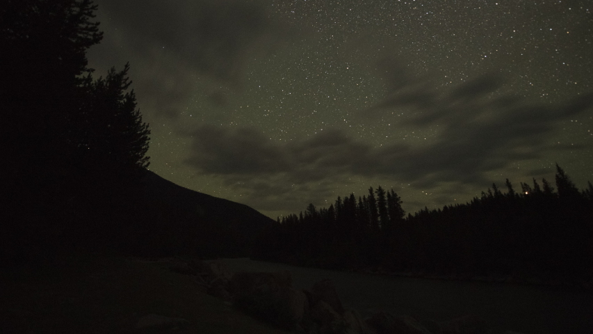 Stars above dark river and forest 4K time lapse