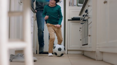 father and son playing with football in kitchen kicking soccer ball child enjoying game with dad at home