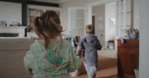 happy children running through house cute little girl chasing brother with toy gun blowing bubbles excited kids enjoying game having fun on weekend morning wearing pajamas 4k