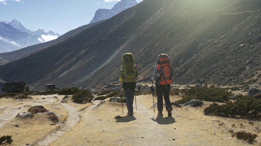 Two women with backpacks are walking along the path in Nepal mountains. Slow motion shot. 4K, UHD