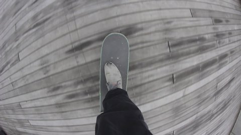 Point of view of skateboarder riding skateboard on the city sidewalk. Skater rolling freestyle in urban environment. Young man holding balance on board, extreme sport
