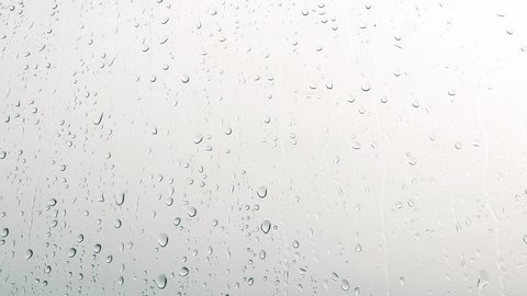 Close-up of water droplets on glass, Rain Rain, Go Away. Large rain drops strike a window pane.