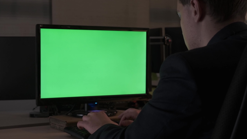 Rear view of a young office male worker sitting at his desk working at computer, chromakey monitor, time lapse. Stock footage. Office concept with working environment, green screen. | Shutterstock HD Video #1034682746