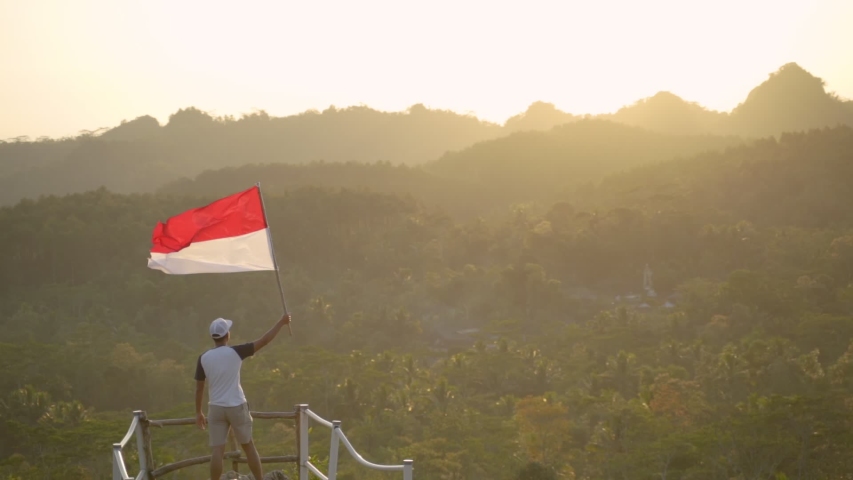 portrait of man on top of the hill in the morning rising indonesian flag celebrating independence day Royalty-Free Stock Footage #1034691272
