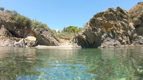 Spain small cove on rocky sea shore seen from water surface and moving camera down underwater, Mediterranean, Costa Brava, Cadaques, Cala Jonquet, Catalonia